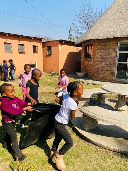 Learners carrying a refuse bag across the school garden