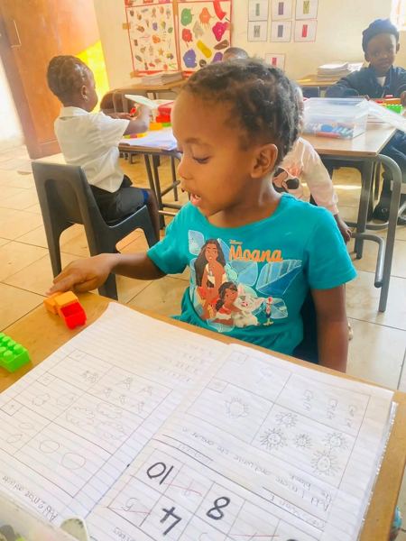 A learner working on addition in her maths workbook